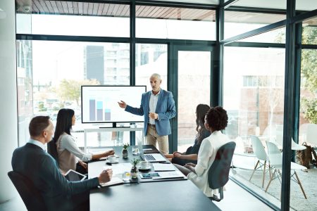 Businesspeople attending a presentation in the boardroom about growth, innovation and development with graphs in a boardroom. Mature man showing great leadership while talking about company vision.